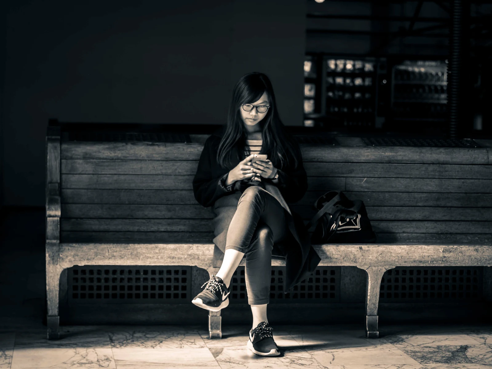女性独自坐在公共座椅上查看手机，表现红桃视频内容专题中的人物日常
